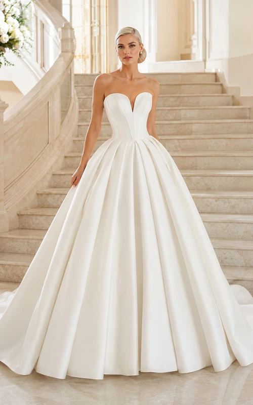 Robe de bal bustier en satin harmonieux, décolleté cœur, traîne cathédrale et plis, idéale pour un mariage à destination.