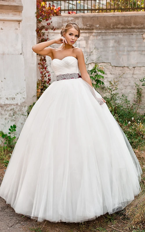 Vestido de gala largo sin mangas con escote corazón, de tul, con cordones, detalle cruzado y joyas en la cintura.