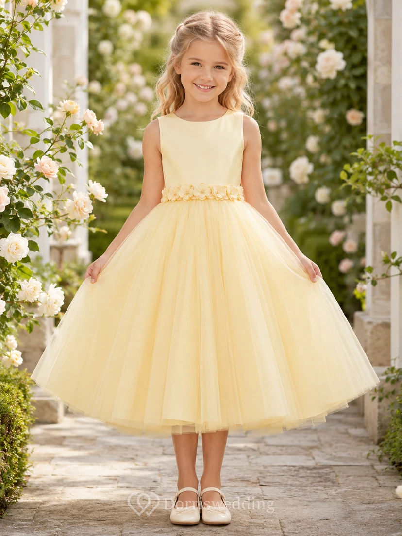 Robe de demoiselle d'honneur jaune beurre en tulle, coupe trapèze, avec applications florales sans manches et volants.