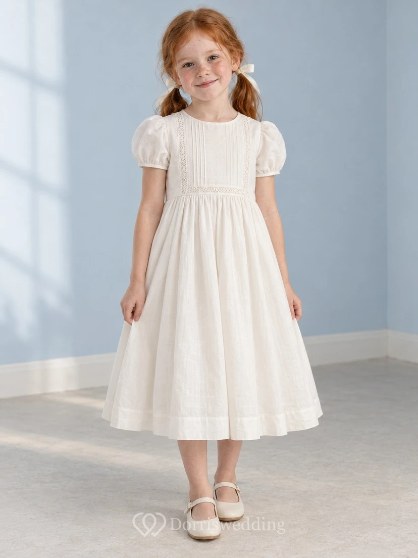 Schlichtes, schlichtes, wadenlanges, elfenbeinfarbenes Blumenmädchenkleid mit kurzen Puffärmeln, zarter Spitzenborte, Abnähern, Raffungen und Knopfleiste am Rücken.