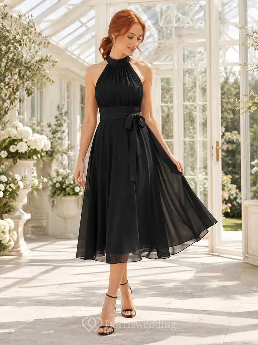 Robe de soirée élégante et moderne en mousseline noire, dos nu, sans manches, coupe trapèze, longueur midi, ornée d'un nœud.