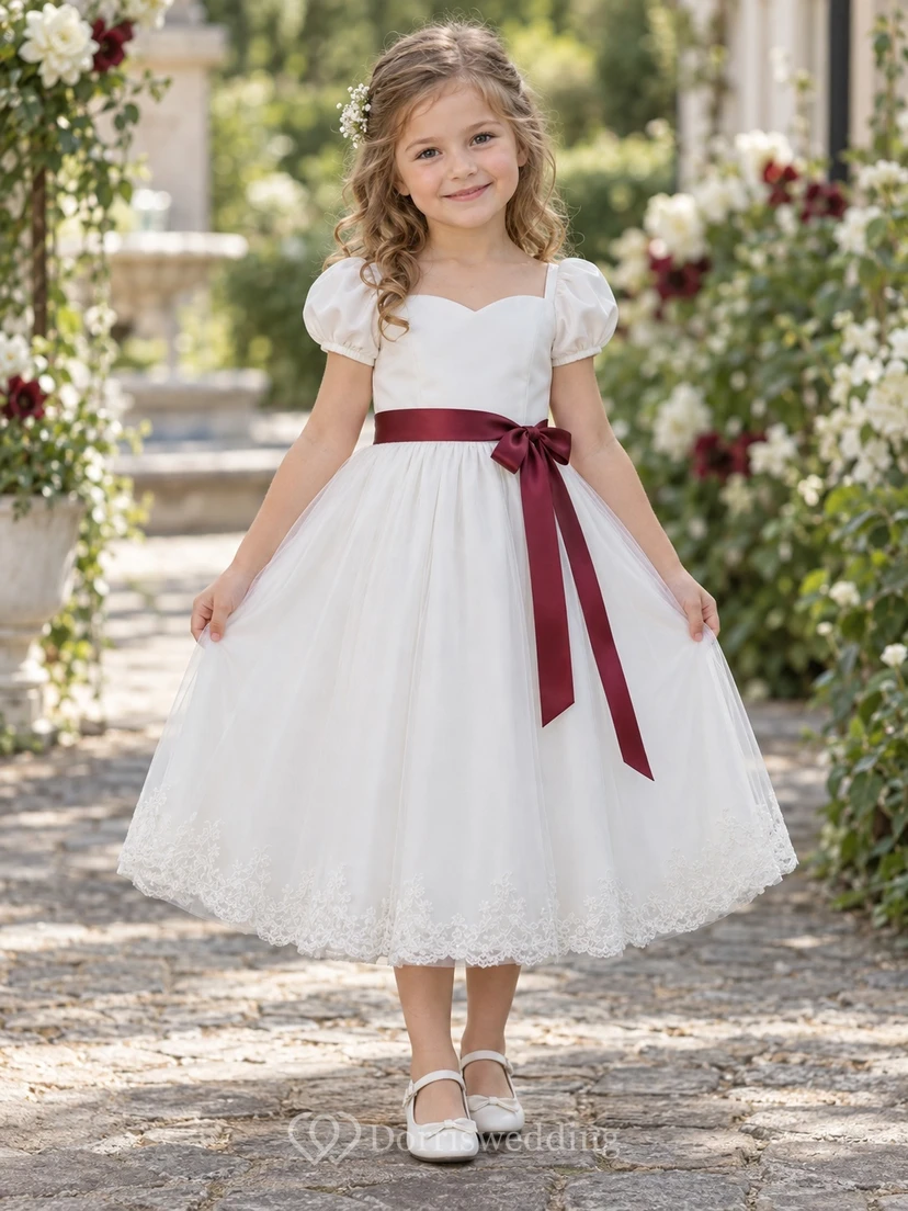 Vestido de niña de flores blanco de corte A con tul, mangas abullonadas, escote corazón, dobladillo de encaje y fajín burdeos.