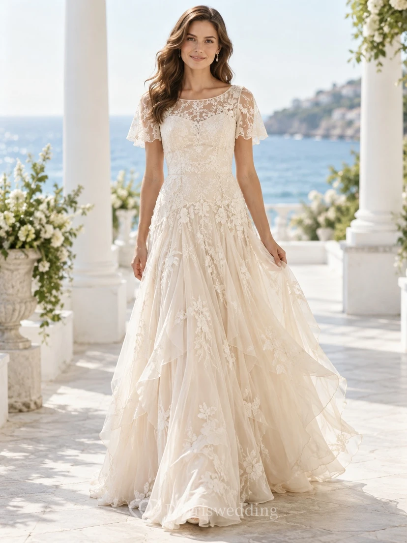 Vestido de novia de encaje floral con capas, mangas cortas y escote ilusión, con cintura baja.