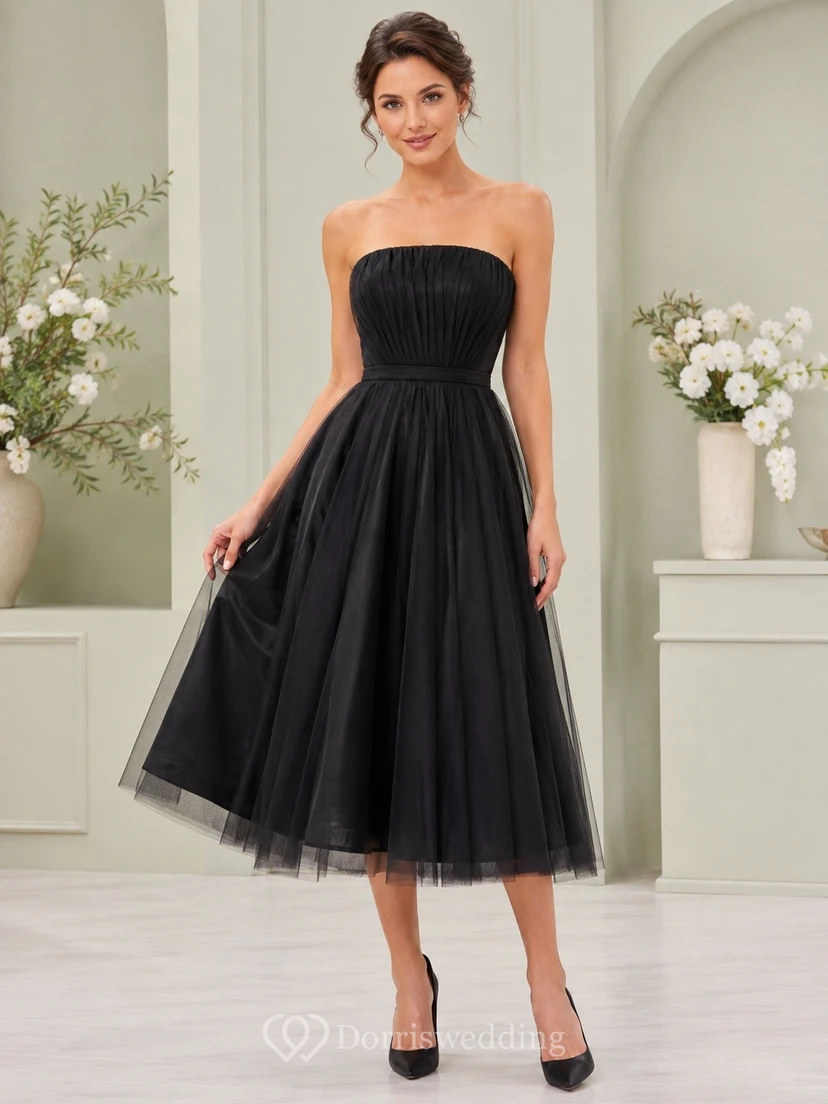 Vestido negro de tul sin tirantes, sin mangas, de corte A, largo hasta la rodilla, con pliegues.