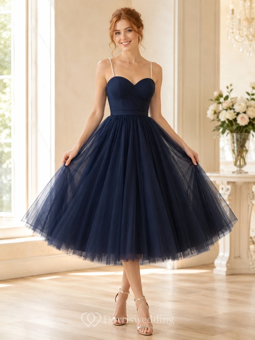 Robe de bal bleu marine en tulle longueur thé, décolleté en cœur, taille structurée, jupe ample et volants.