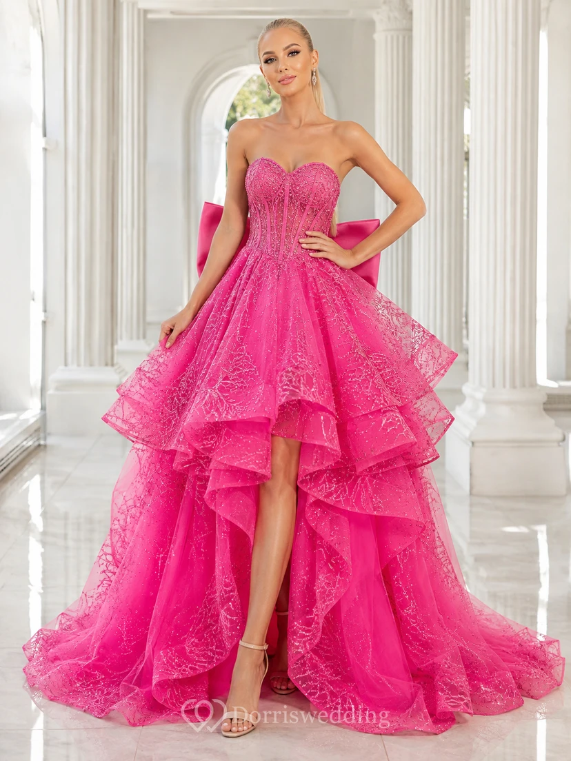 Vestido de fiesta fucsia sin tirantes con lazo de encaje, volantes en cascada, corte A asimétrico y cola de corte clásico.