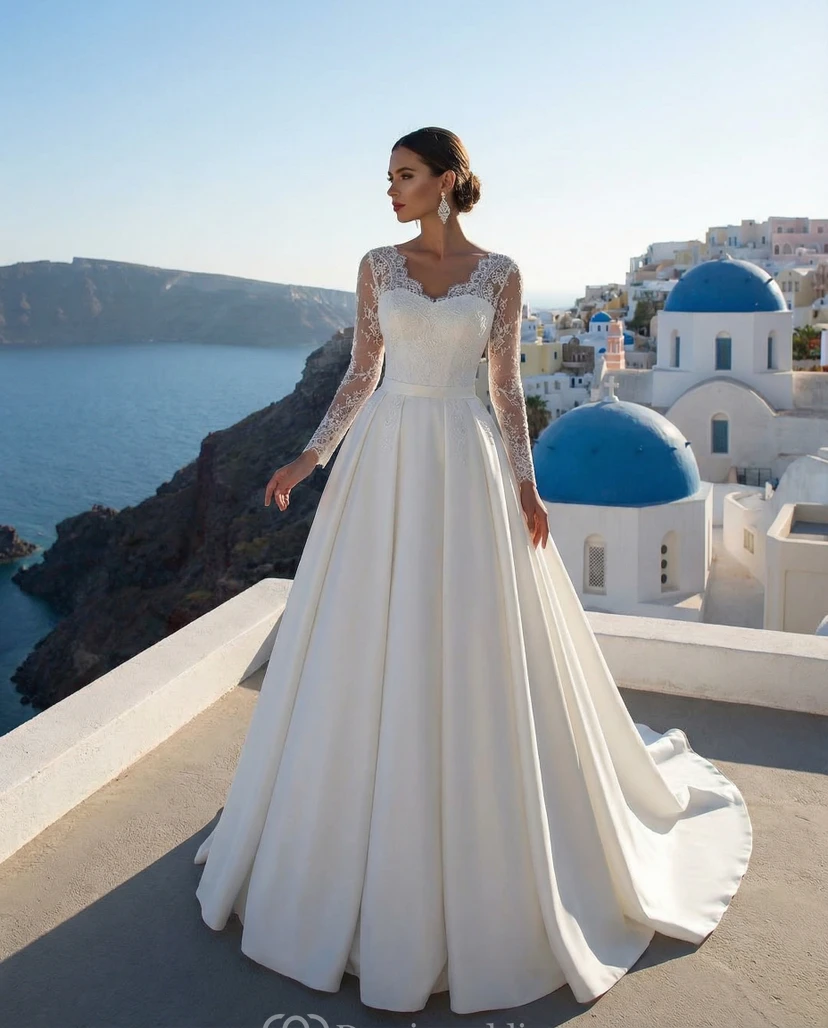Vestido de novia de satén estilo princesa con mangas largas de encaje y cola catedral.