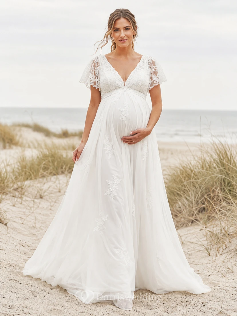 Vestido de novia de playa premamá con escote en V, mangas cortas de encaje y falda imperio de tul.