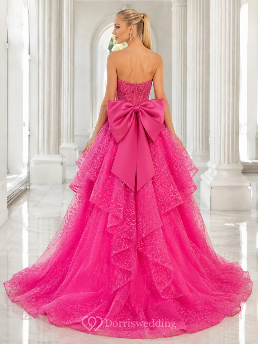 Vestido de fiesta fucsia sin tirantes con lazo de encaje, volantes en cascada, corte A asimétrico y cola de corte clásico. view 2