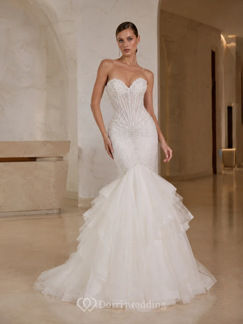 Robe de mariée sirène bustier en satin et tulle brillant, décolleté cœur et traîne à volants superposés, idéale pour une salle de bal.