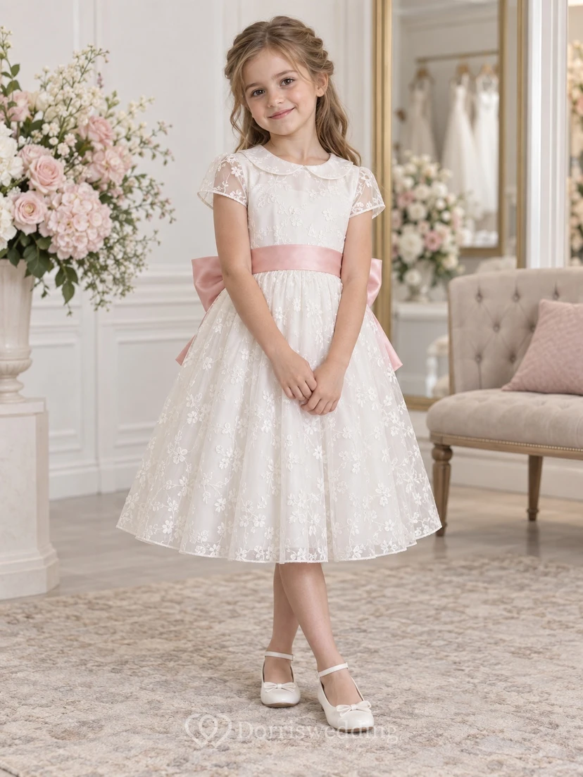 Vestido de niña de flores vintage blanco con estampado floral, corte en A, mangas cortas de encaje y fajín rosa, largo hasta la rodilla.