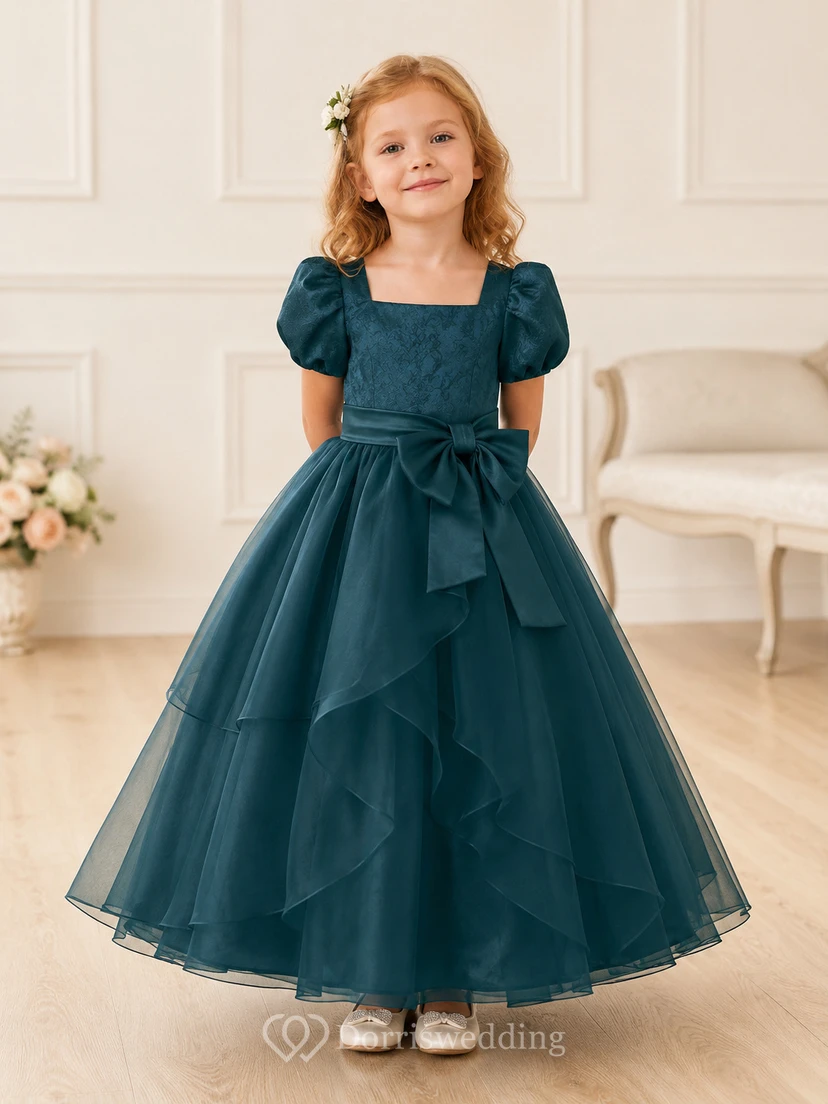 Robe de demoiselle d'honneur bleu turquoise en tulle à volants superposés, coupe trapèze, manches bouffantes et nœud.