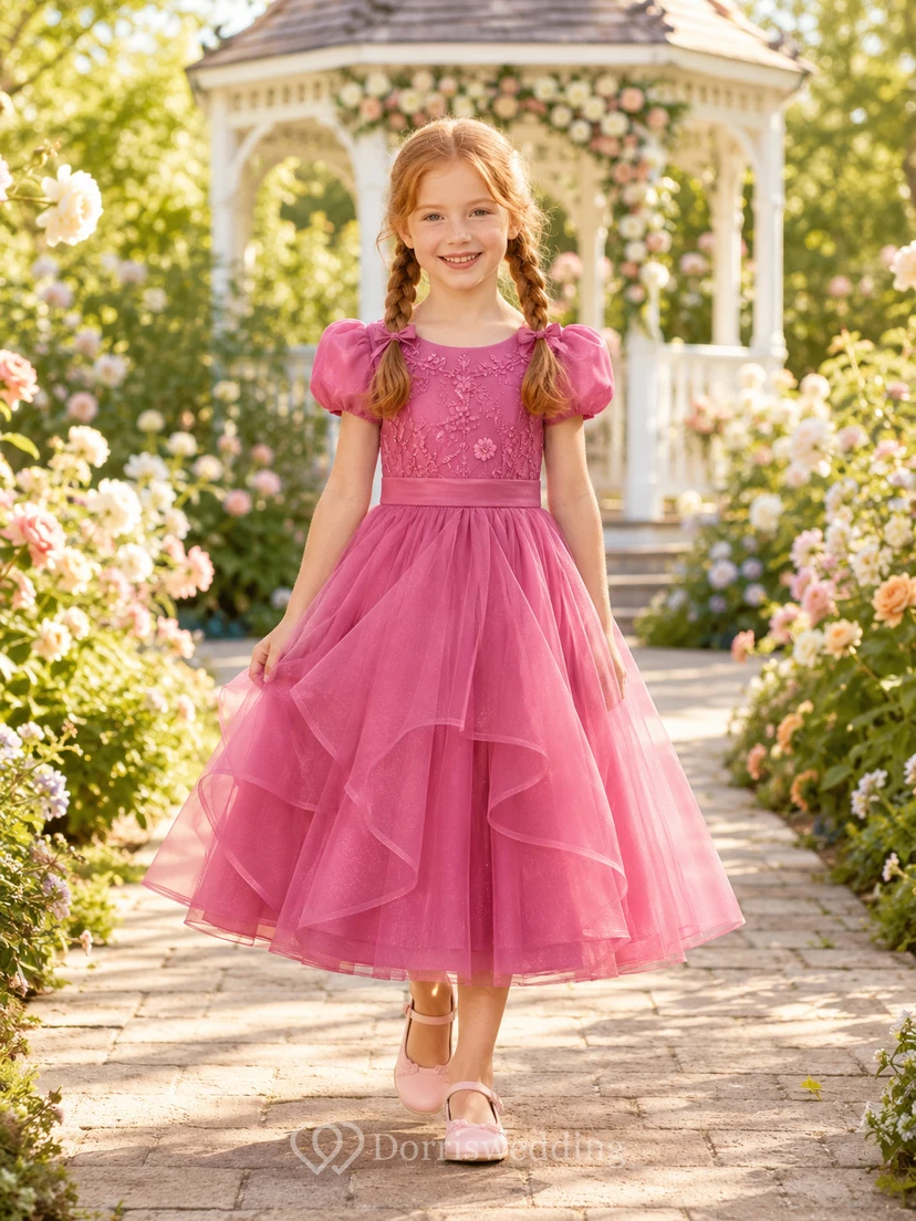 Robe de demoiselle d'honneur rose framboise en tulle superposé, coupe trapèze, manches bouffantes à volants et nœud.