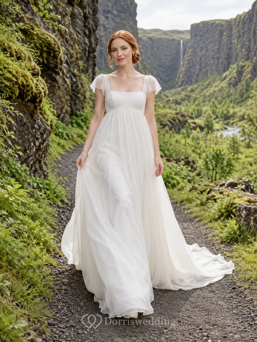 Vestido de novia de organza con escote cuadrado estilo imperio, mangas cortas con volantes y cola de corte.