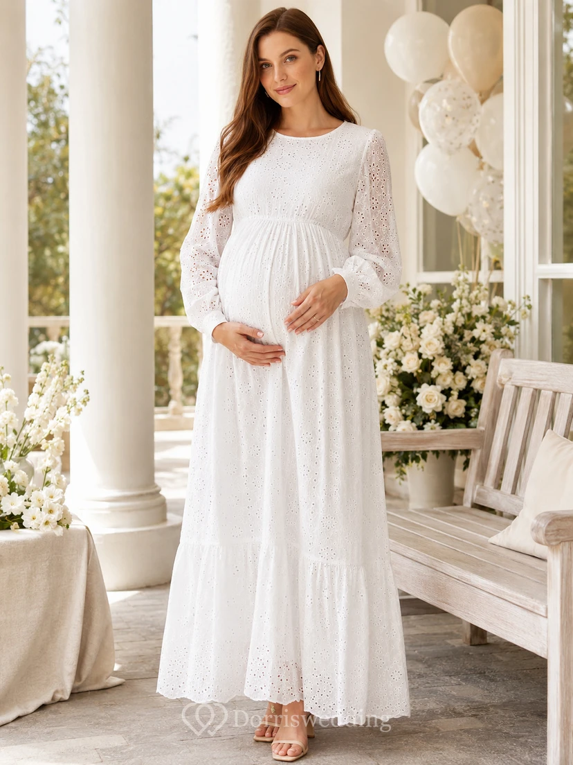 Vestido blanco de maternidad con cuello joya, manga larga, encaje calado y falda escalonada hasta el tobillo.