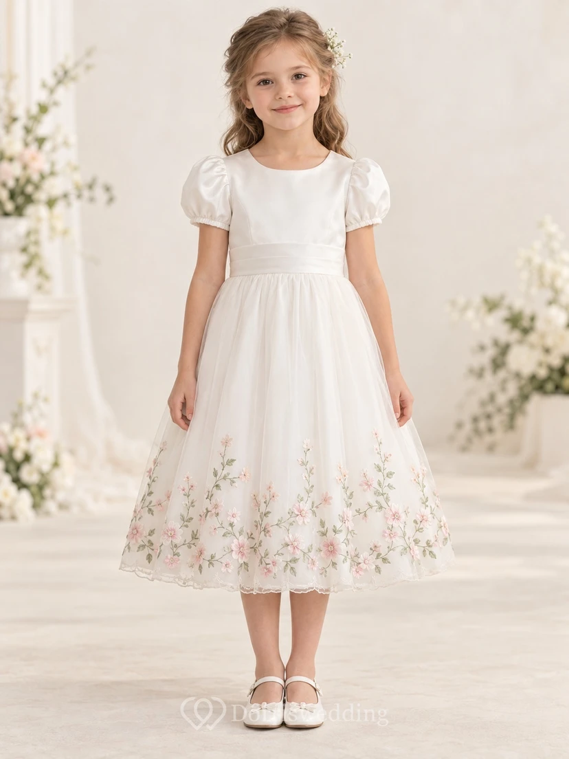 Vestido de niña de flores color marfil, corte en A, manga abullonada, dobladillo bordado con motivos botánicos y lazo en la espalda.