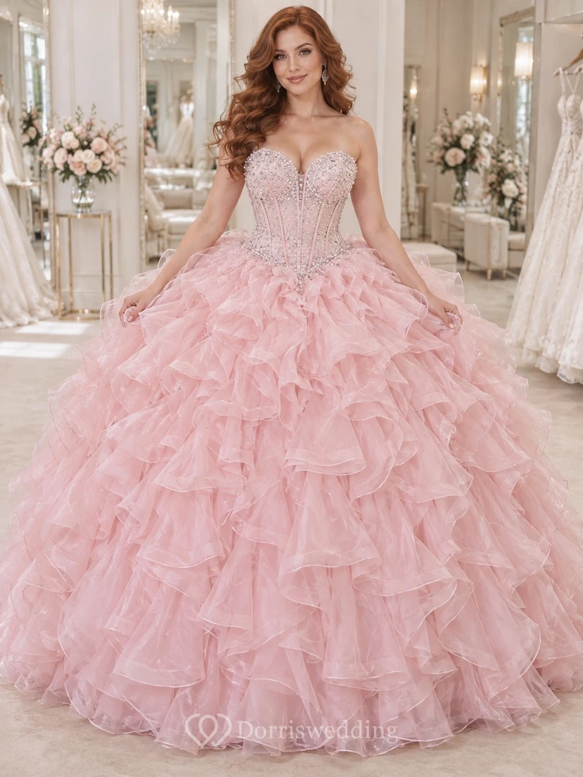 Vestido de novia de gala rosa palo sin tirantes con escote corazón, bordado con cuentas y volantes de organza en cascada.