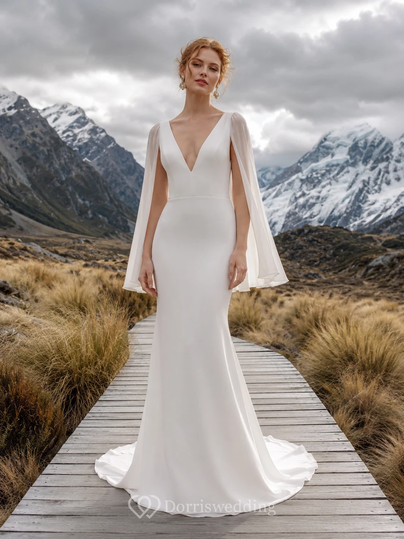 Robe de mariée fourreau en satin et mousseline, décolleté plongeant en V, manches cape et traîne.