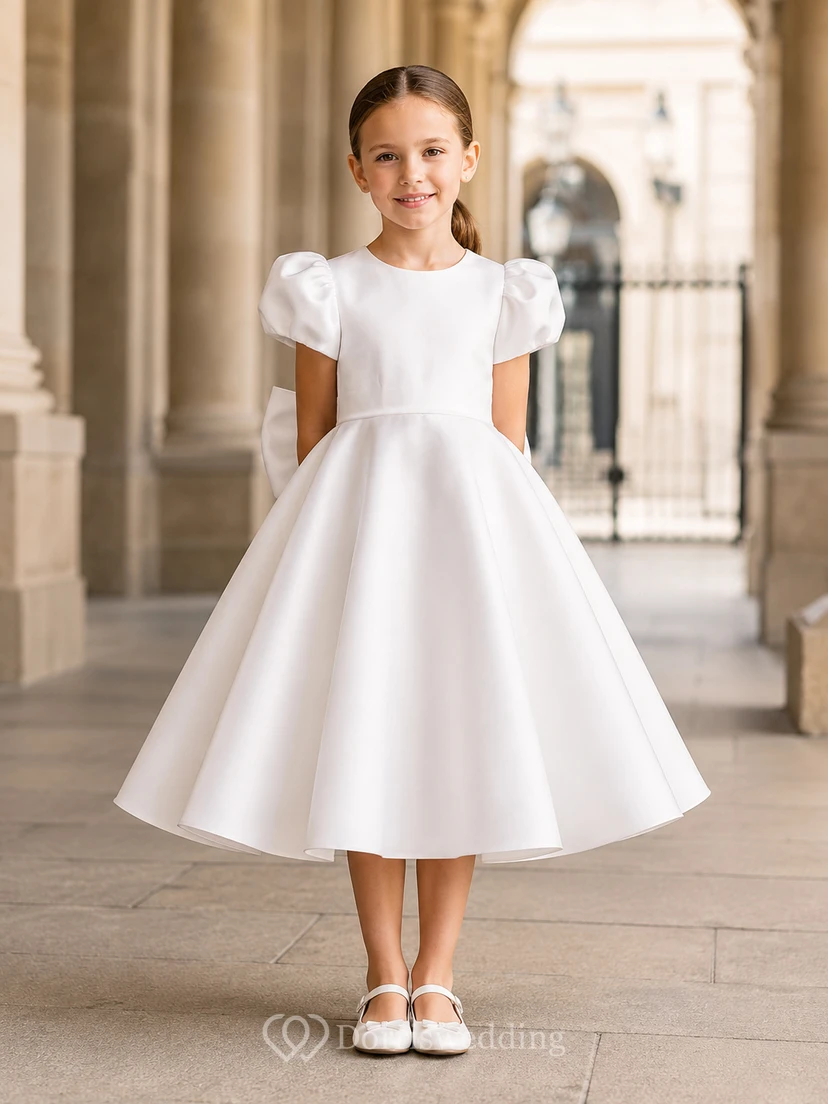 Vestido de niña de flores blanco de satén con mangas abullonadas, corte en A, cuello joya, falda hasta la rodilla y detalle de lazo.