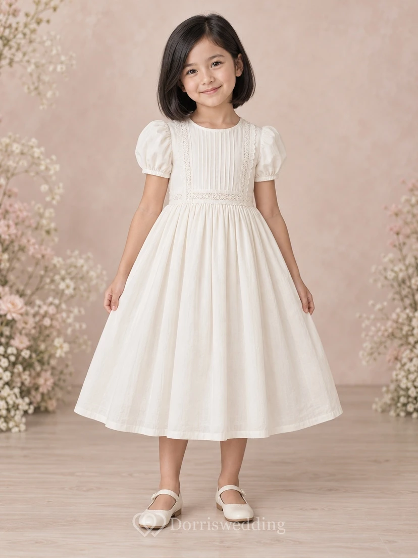 Schlichtes, schlichtes, wadenlanges, elfenbeinfarbenes Blumenmädchenkleid mit kurzen Puffärmeln, Muschelsaum, Spitzenborte, Abnähern, Raffungen und Knopfleiste am Rücken.