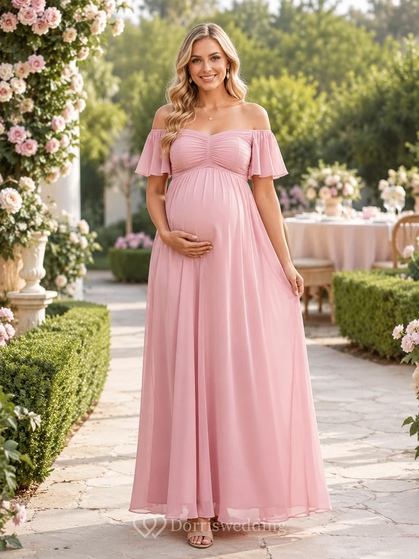 Robe de maternité rose poudré en mousseline rose poudré, épaules dénudées, manches papillon, style empire, longueur au sol, idéale pour une garden-party.