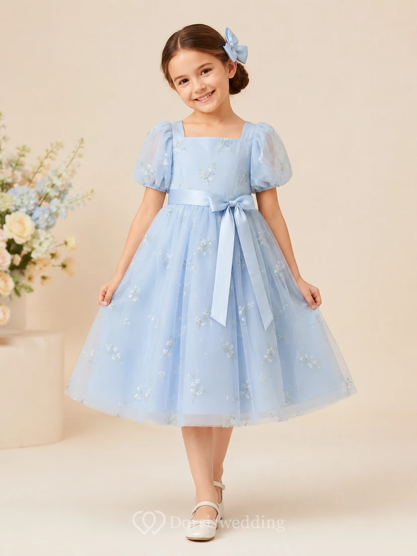 Sencillo vestido de niña de flores de tul con corte en A, cuello joya, falda a media pierna y falda plisada.