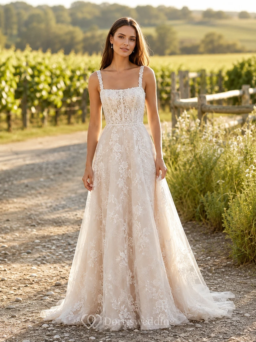 Robe de mariée en dentelle et tulle, coupe trapèze, col en V, sans manches, traîne chapelle, corset lacé au dos.