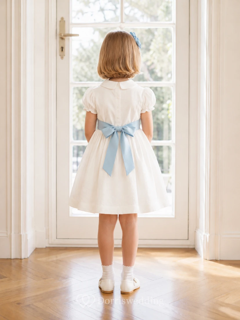 Vestido de niña de flores de satén color marfil con corte en A, mangas cortas abullonadas, escote joya y falda hasta la rodilla con detalles de lazos. view 2