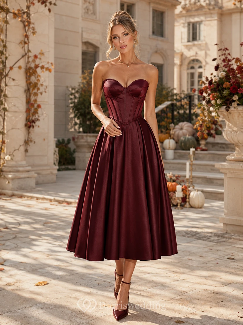 Vestido de fiesta largo hasta la rodilla de satén color burdeos sin tirantes con escote corazón y corsé.