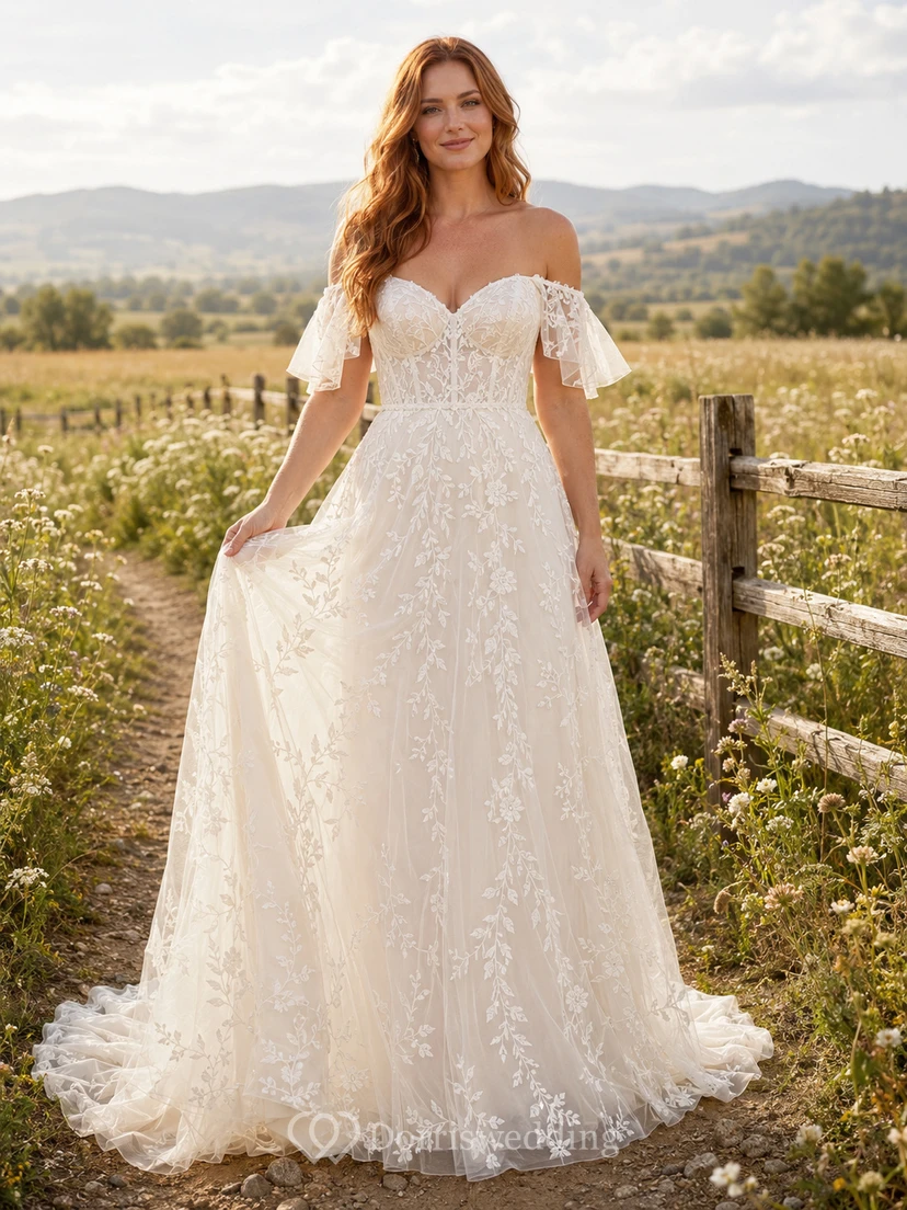 Robe de mariée champêtre en tulle et dentelle, coupe trapèze, bretelles spaghetti, traîne chapelle et dos nu plongeant en V.