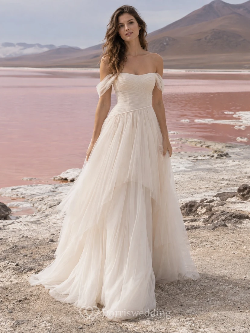 Vestido de novia de tul con escote Bardot, corte en A, corpiño fruncido y falda asimétrica de capas.