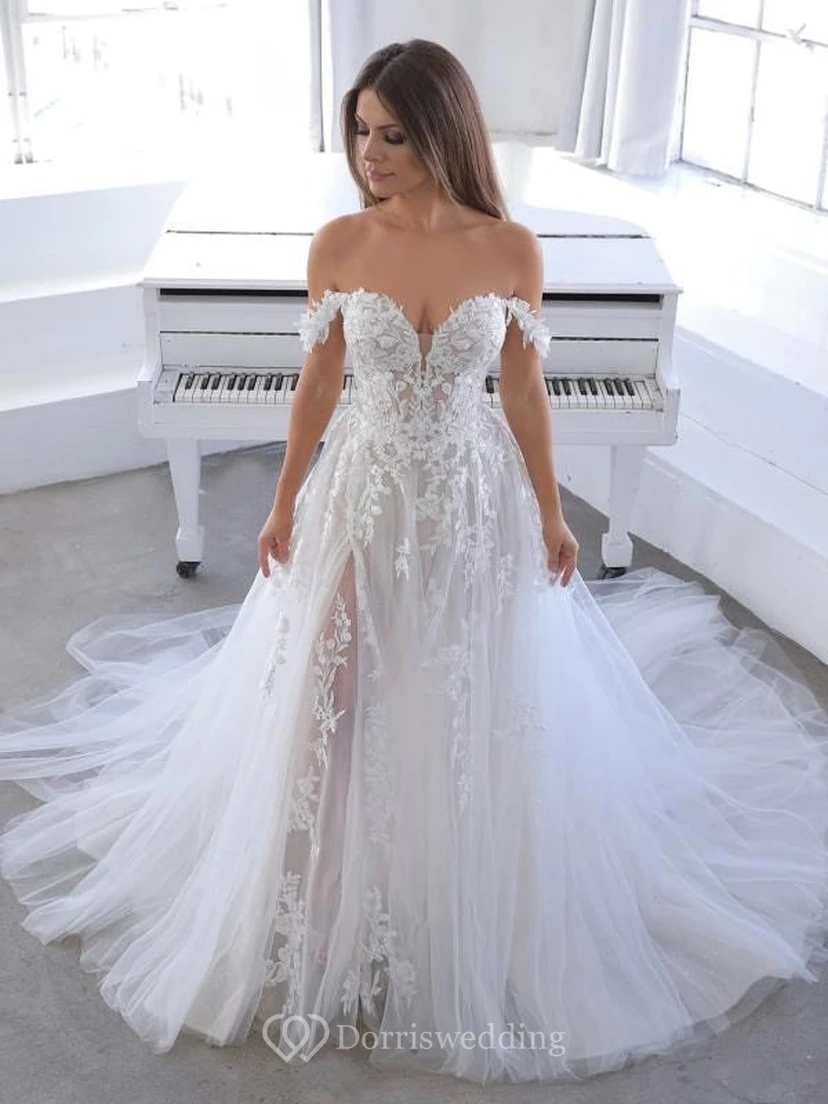 Vestido de novia etéreo de corte imperio con tul, hombros descubiertos y apliques de encaje.