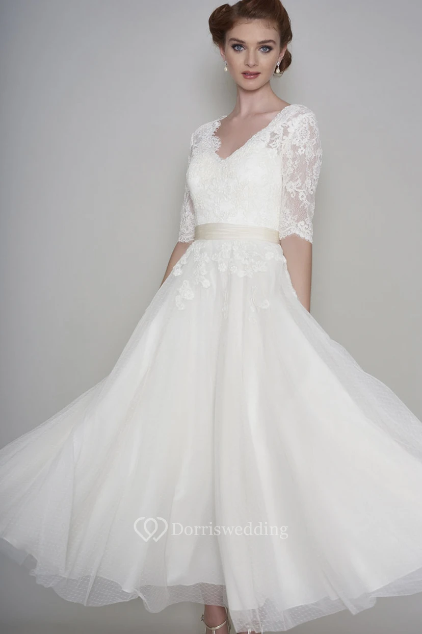 Robe de mariée courte en dentelle et organza, manches mi-longues, longueur cheville, ornée d'appliqués.