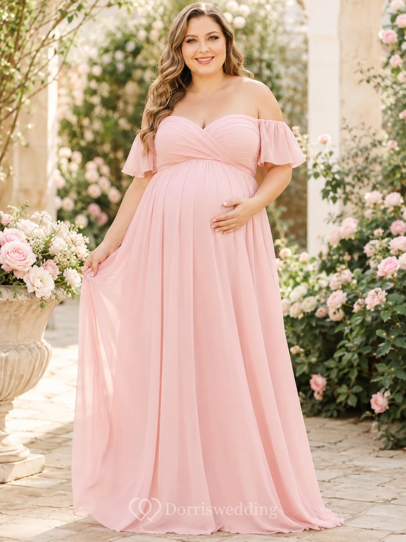 Vestido de maternidad romántico de gasa color rosa empolvado con hombros descubiertos, mangas con volantes y corte imperio, largo hasta el suelo.