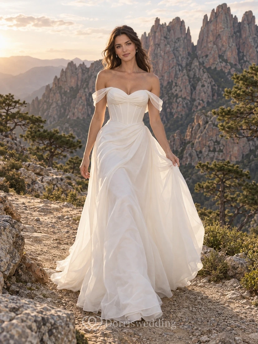 Vestido de novia romántico de organza con escote de hombros descubiertos, corte en A, sin mangas, fruncido y cola larga.