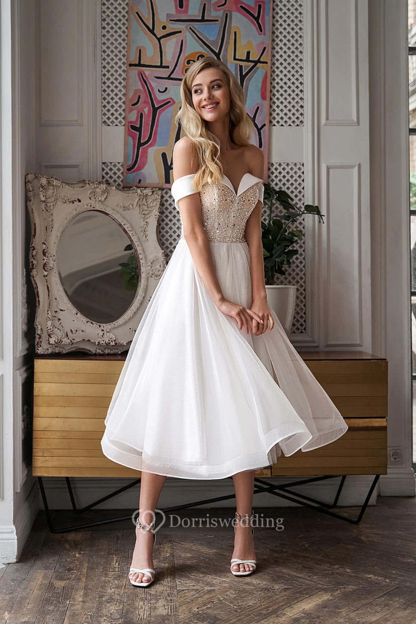 Elegante vestido de novia de corte A con corpiño de hombros descubiertos y detalles de cuentas, largo hasta la rodilla.