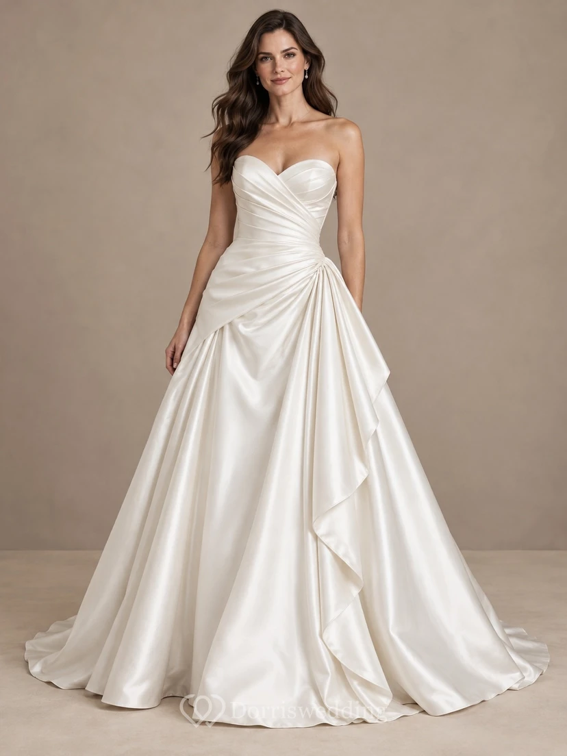 Vestido de novia sencillo, sin tirantes, con escote corazón asimétrico y cola larga de satén drapeada.