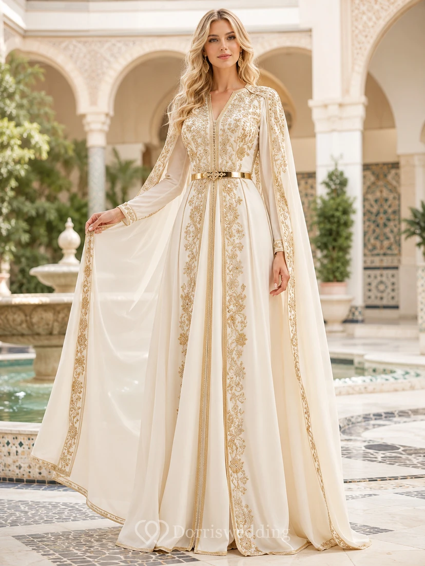 Vestido de noche largo hasta el suelo, de satén, con cuello alto, mangas tipo capa y bordado dorado, en color marfil.
