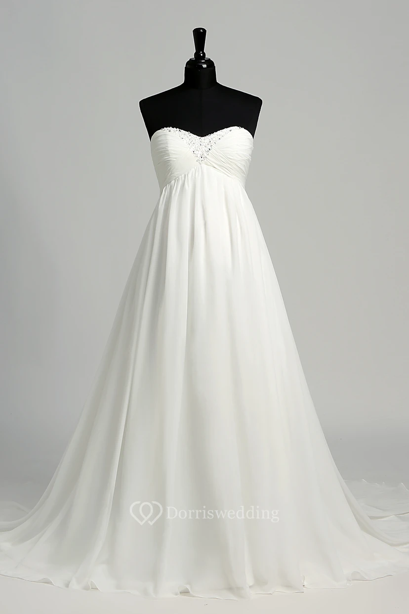 Robe de mariée en mousseline de soie, coupe trapèze, décolleté cœur sans manches, longueur au sol, avec traîne courte.