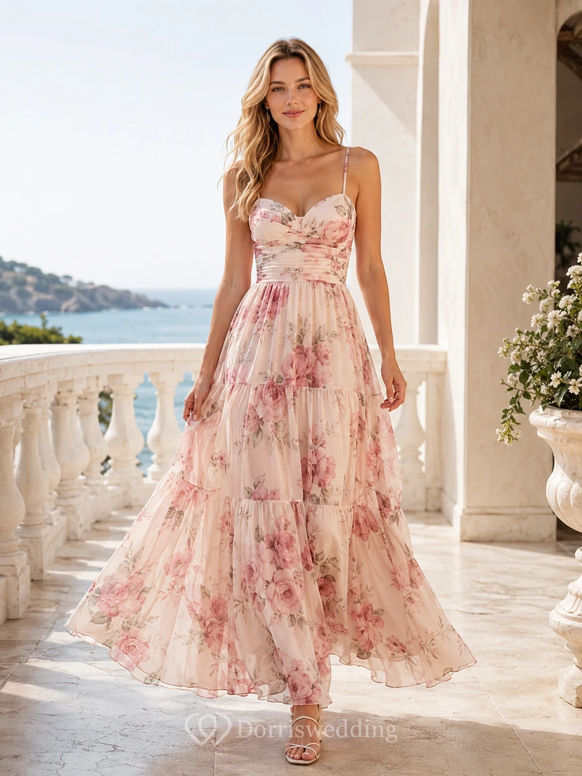 Robe de bienvenue en tulle à fines bretelles et décolleté cœur, ornée de fleurs rose poudré et arrivant à la cheville, coupe trapèze, à bretelles spaghetti et bustier cœur.