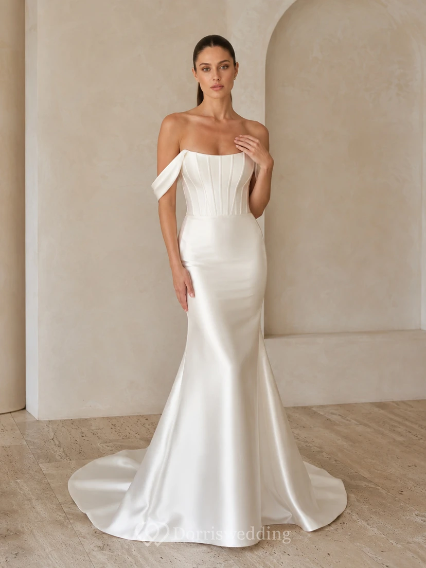 Robe de mariée minimaliste en satin discret, épaules dénudées, manches courtes, fourreau et traîne, idéale pour un mariage à destination.
