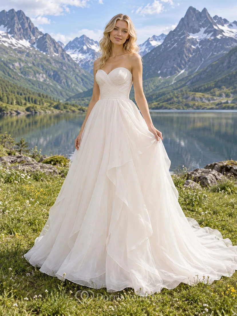 Vestido de novia romántico sin tirantes de organza con escote corazón, corte en A, corpiño fruncido y volantes en cascada.
