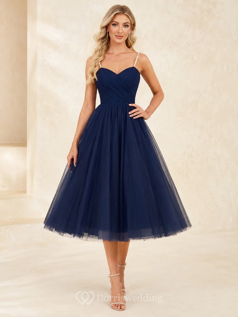 Robe de bal bleu marine en tulle, longueur thé, décolleté cœur, bretelles perlées, jupe ample et coupe trapèze.