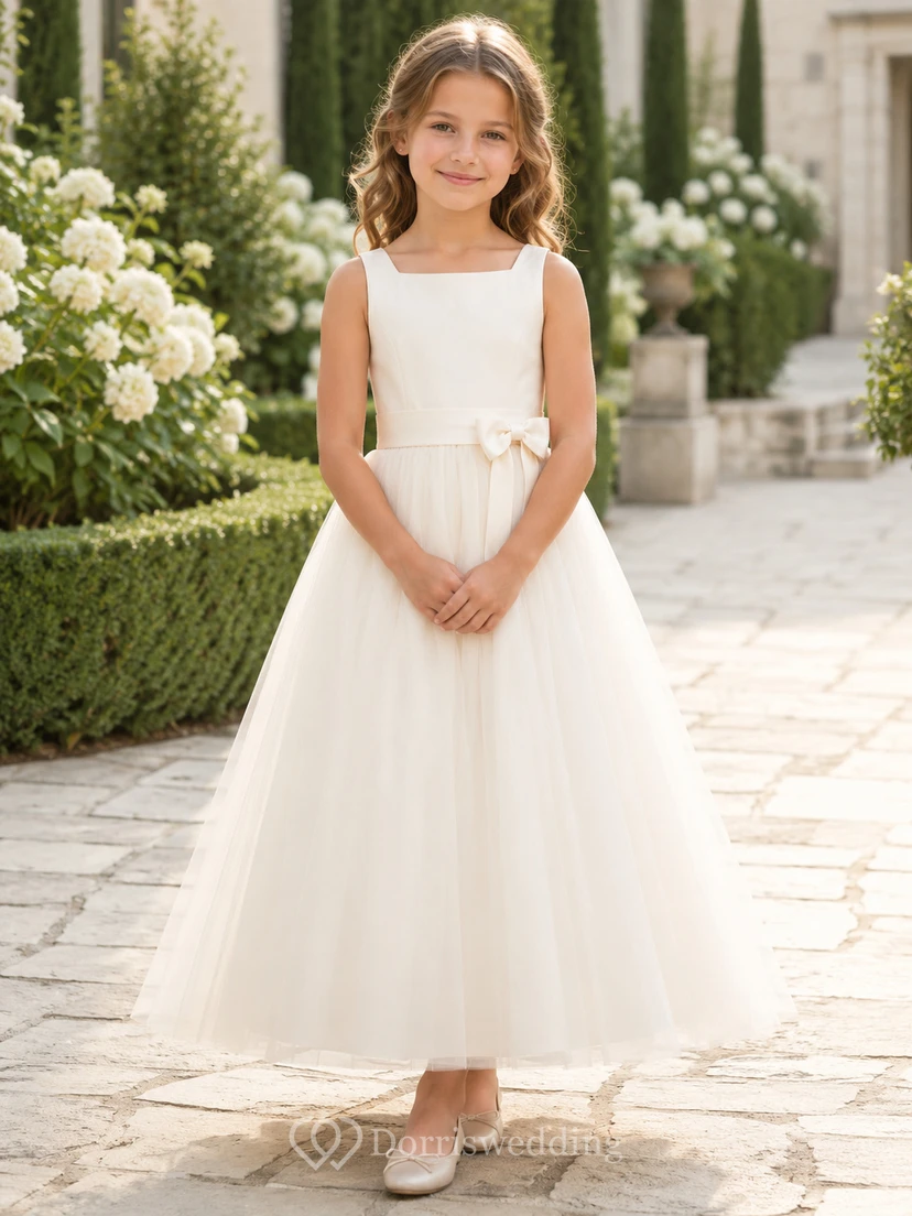 Robe de demoiselle d'honneur blanche sans manches en tulle, coupe trapèze, encolure carrée et jupe mi-longue ornée de détails floraux.