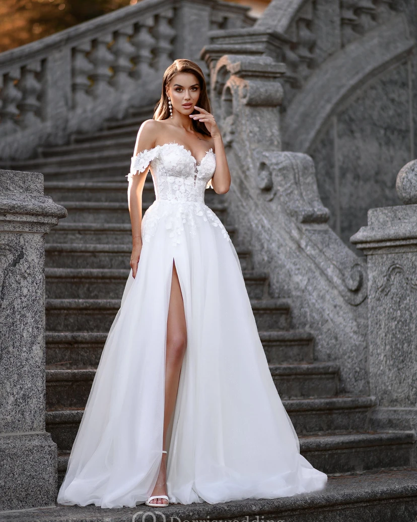 Vestido de novia de corte A con escote corazón, hombros descubiertos y abertura frontal, de encaje y estilo princesa.