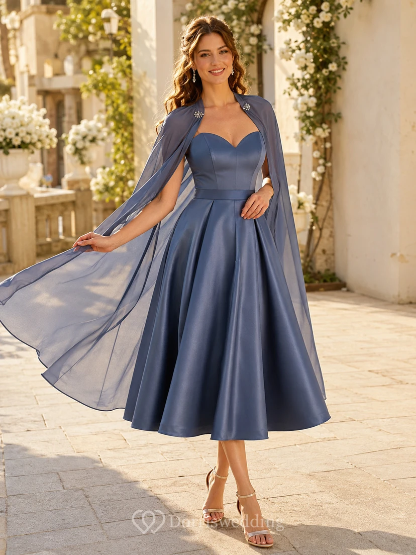 Vestido de invitada midi completo de satén azul acero con escote corazón y capa desmontable.