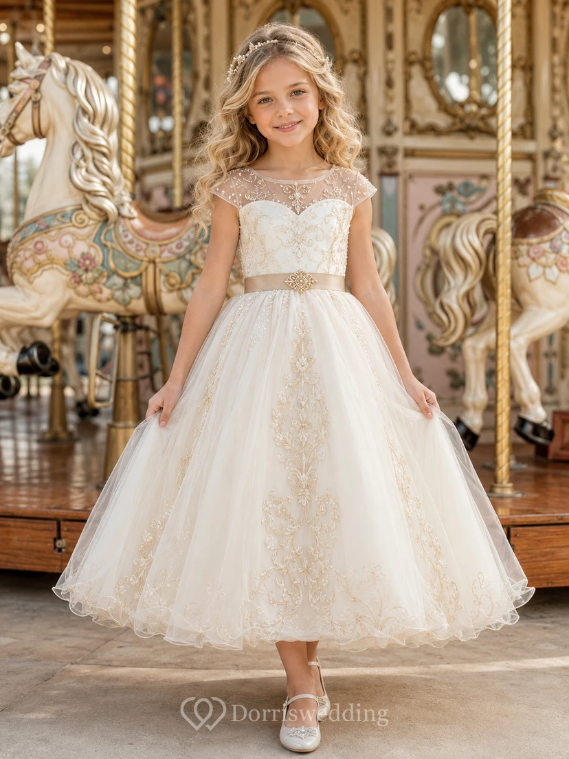 Vestido de niña de las flores color marfil con mangas cortas transparentes, corpiño con escote corazón, falda de tul en línea A hasta la rodilla y lazo bordado dorado en la cintura.