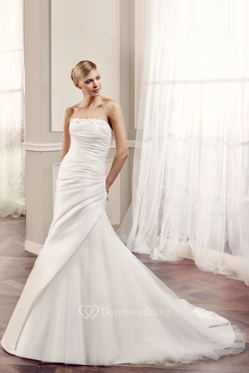 Robe de mariée sirène en satin, sans manches, bustier, dos nu et perles, avec drapé latéral sur les côtés.