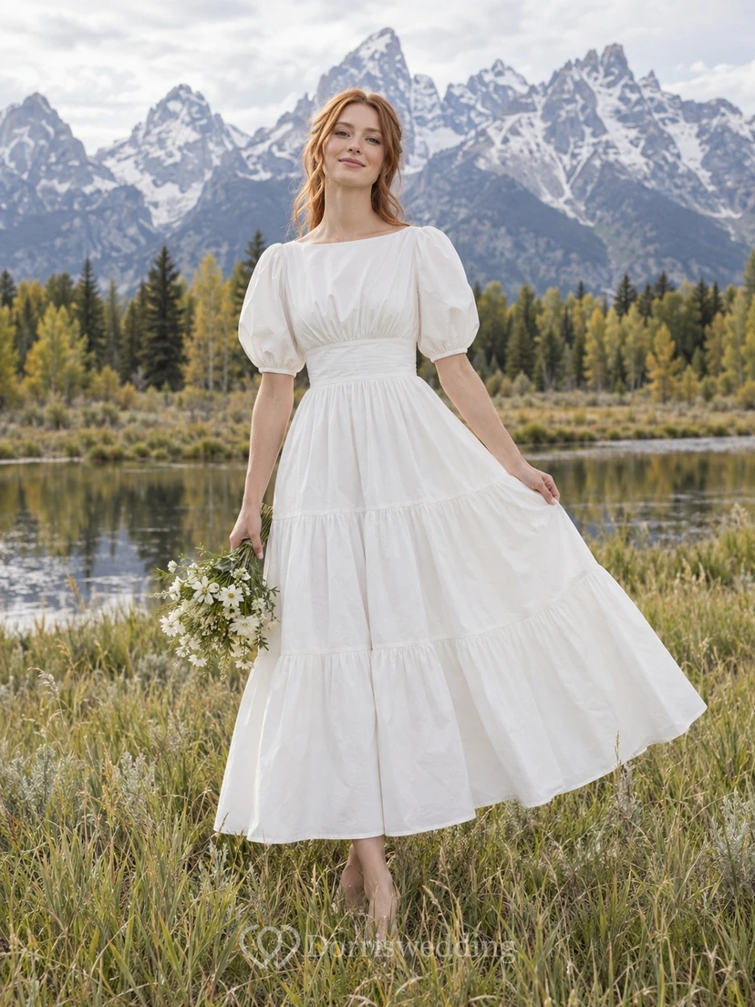 Vestido de novia sencillo de popelina tejida con escote barco, manga corta y volantes, largo hasta la rodilla.