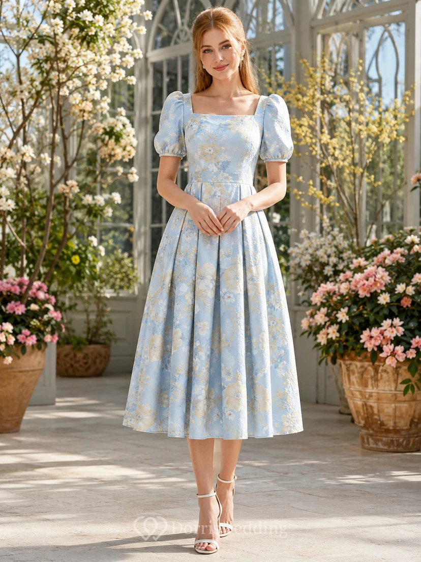 Robe mi-longue à fleurs bleues, col carré et manches bouffantes, encolure carrée.